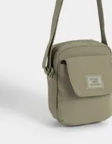 Bandolera verde militar de tela deportiva con bolsillo frontal con solapa, correa regulable, cierre superior y tag frontal con la inscripción "No Bad Vibes Allowed".