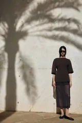 Remera larga marrón en punto pesado de algodón. Modelo con escote bote, hombros caídos y mangas amplias al codo. Cintura entallada con pinzas apenas acolchadas adelante y atrás.