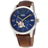 Reloj Fossil automático con caja plateada, esfera azul con números romanos y agujas doradas, y correa de cuero marrón.