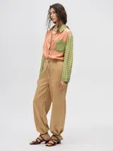 Mono largo de jean celeste con corte holgado, cintura elastizada con cordón ajustable, sin mangas, cuello camisero y cierre frontal con botones. Presenta bordados de motivos playeros en el pecho.