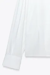 Camisa blanca de popelín con cuello solapa y manga larga.