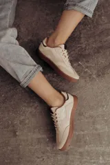 Zapatillas bajas de cuero color marrón con suela de goma color caramelo y cordones marrones.