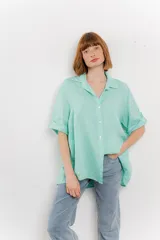 Camisa color verde agua, confeccionada en lino, de corte amplio, con cuello camisero, botones en el frente y mangas 3/4 que se pueden arremangar.