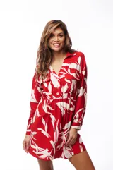 Vestido corto tipo camisero color rojo con estampado de hojas blancas, cuello camisero, cierre frontal con botones, mangas largas y elástico en la cintura.