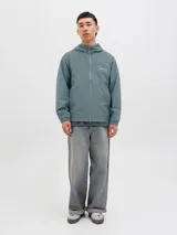 Campera softshell color celeste con capucha ajustable con cordón, mangas largas con puños de canalé, cierre frontal con cremallera y bolsillos delanteros.