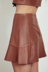 Minifalda acampanada de cuero color caramelo con costuras decorativas en hilo blanco.