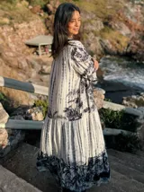 Vestido largo de estilo campesino con estampado de palmeras en tonos blanco y negro, con escote en V y mangas largas abullonadas.