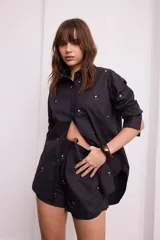 Short negro con bordado de flores rosas, con elástico en la cintura y cordón ajustable.