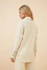 Camisa estilo leñador color beige con textura de espiga, de manga larga con puños abotonados, cuello clásico, cierre frontal con botones y dos bolsillos de parche con solapa abotonada en el pecho.