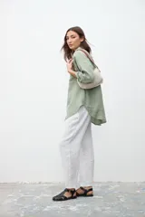 Bolso de hombro tejido a crochet color crema, con asas cortas de cuero marrón.