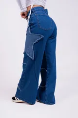 Pantalón de jean azul con parches en forma de estrella de un tono más claro y bordes desflecados.