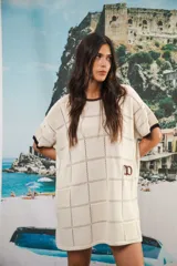 Vestido corto negro con patrón calado cuadrado, cuello redondo y mangas cortas con terminaciones a contratono en blanco.