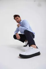 Zapatillas blancas de cuero con cordones y suela de goma negra.