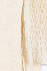 Top mostaza de cuello barco y manga larga con textura. Tiene lazadas ajustables en el bajo.