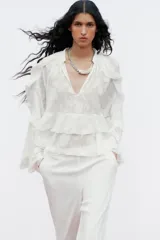 Camisa blanca de cuello redondo con escote en V y mangas largas acampanadas con volantes.