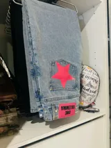 Pantalón de jean gris oscuro con corte recto y bolsillos traseros con apliques de estrellas rojas.