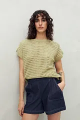 Chaleco tejido color crudo con diseño calado, cuello redondo y mangas cortas. Corte holgado.