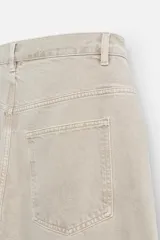 Pantalón de jean color beige, de corte amplio y tiro alto. Tiene cinco bolsillos, cierre frontal con botones y detalle de costuras laterales dobles.