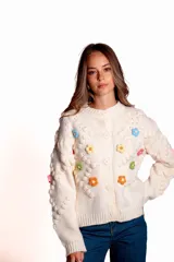 Saco de punto color rojo, con cuello polo y cierre frontal de botones blancos. Presenta flores bordadas en relieve de diferentes colores (azul, amarillo, verde, naranja, rosado) y mangas largas con diseño de burbujas.