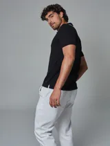 Remera tejida tipo polo color negro, de corte regular fit, con cuello y puños con ribete en contraste de color blanco, cartera con tres botones y logo bordado en la pechera.