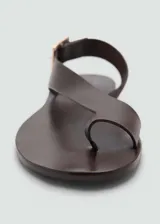 Sandalias negras de cuero con tira cruzada y hebilla dorada.
