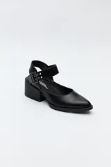 Zapato negro tipo zueco con acabado charol, tira ancha con hebilla metálica y taco ancho de altura media.