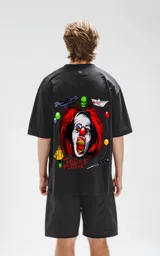 Remera negra de corte oversize con estampado del payaso Pennywise de la película IT, un cráneo verde, un barco de papel, globos y la frase "Todos Flotan".
