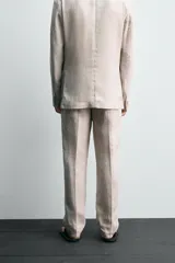 Pantalón de vestir color beige claro, confeccionado en lino, de corte recto, con bolsillos laterales y traseros.