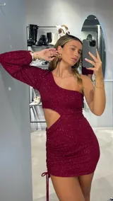 Vestido corto de fiesta color bordó con brillos, de un hombro con manga larga abullonada y corte en la cintura.