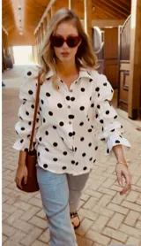 Camisa blanca con lunares negros, de corte holgado y mangas largas abullonadas con puños elásticos.