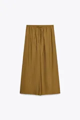 Falda midi color ocre de tejido arrugado con cintura elástica ajustable con cordones y bolsillos laterales ocultos en la costura.
