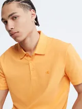 Chomba color naranja de manga corta, con cuello polo y tapeta de dos botones. Tiene el logo de Calvin Klein bordado en el pecho. Corte regular.