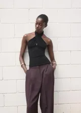 Top negro sin mangas, de diseño entallado, con cuello halter cruzado.