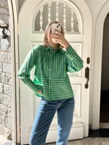 Camisa verde con rayas verticales azules, de corte recto y manga larga.