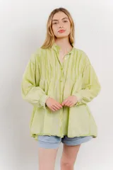 Camisa oversize blanca de algodón con pliegues frontales.