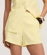 Short de sastrería color amarillo claro, de tiro alto con cintura elástica y cierre tradicional. Presenta frisos verticales en la parte delantera.