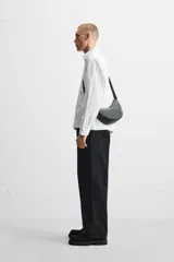 Camisa cropped fit confeccionada en tejido de algodón a rayas verticales negras sobre fondo blanco. Cuello solapa y manga larga acabada en puño con botones. Bolsillos frontales de plastrón con solapa. Cierre frontal de botonadura.