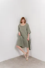 Vestido midi de lino con corte relajado y silueta fluida. Presenta escote redondo, mangas 3/4 y bolsillos laterales. Diseño minimalista y atemporal ideal para el verano.
