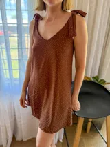 Vestido corto marrón con estampado de lunares blancos, escote en V y breteles finos con lazos en los hombros.
