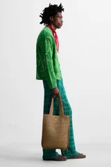 Bolso tipo shopper color marrón claro, con acabado trenzado. Tiene un compartimento principal con cierre de imán y un bolsillo plano interior. Cuenta con dos asas de mano.