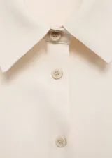 Mono corto color crema, sin mangas, con cuello camisero, cierre frontal con botones y cinturón ajustable.