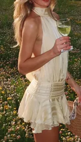 Vestido corto color amarillo pálido con cuello halter y falda con volados.