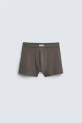 Pack de tres calzoncillos tipo bóxer de tejido elástico con acabado aterciopelado y cintura elástica. Incluye un bóxer color gris claro, uno gris oscuro y uno marrón.