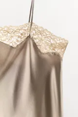 Vestido corto tipo lencero confeccionado en mezcla de seda color gris topo. Presenta escote recto, tirantes finos y detalle de encaje color crema en el escote.