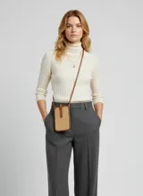 Bolso pequeño tipo bandolera para celular, tejido en rafia color natural, con ribetes y correa de cuero sintético color coñac. Posee cierre de broche en la solapa.