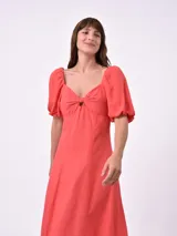 Vestido midi color salmón, con escote cuadrado, mangas cortas abullonadas y detalle de abertura en el pecho.
