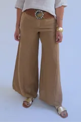 Pantalón camel de corte palazzo, tiro alto y confeccionado en lino. Presenta cintura con trabillas y cinturón trenzado con hebilla circular.