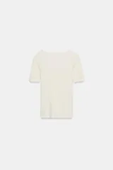 Camiseta negra de corte ajustado, con escote en pico y mangas tres cuartos. Presenta detalle de encaje en el escote.