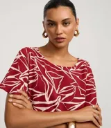 Enterito corto de poliéster con estampado abstracto en tonos borgoña y blanco. Tiene mangas cortas, escote redondo, cierre en la espalda, elástico en la cintura y lazo para ajustar.