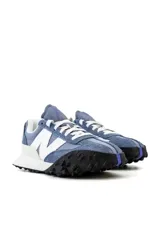 Championes urbanos New Balance de gamuza azul con detalles en gris y blanco. Presentan el logo 'N' en el lateral, cordones blancos y suela de goma negra con detalles en blanco.